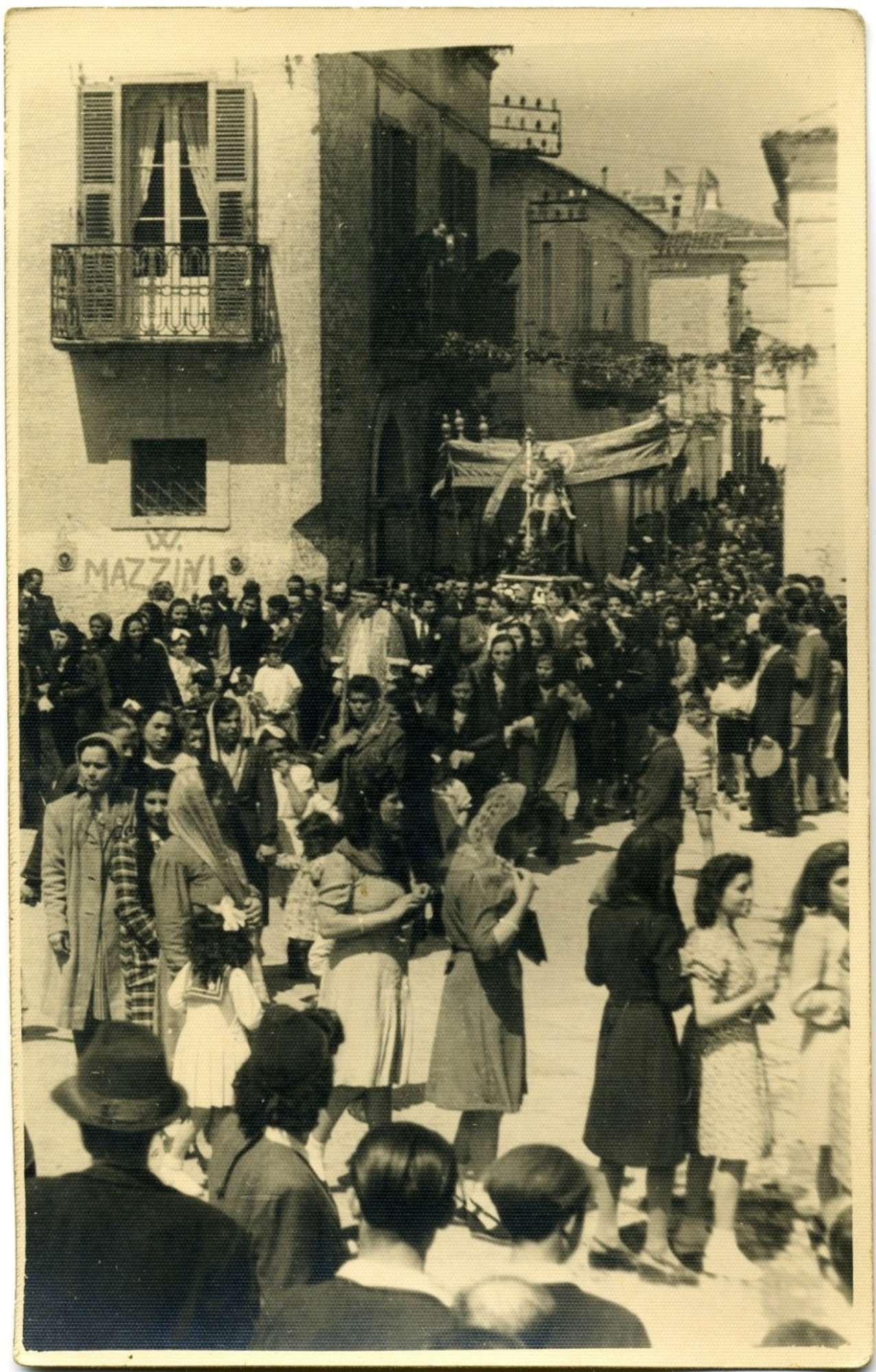 Fedeli di tutte le età seguono la processione per le vie del borgo antico (fine XIX-inizio XX secolo)